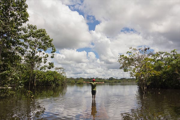 standing knee deep in amazon with arms spread