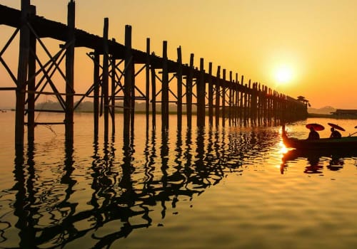 Boat approaching tall bridge at sunset